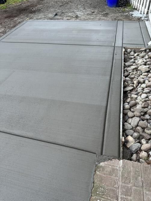 A concrete driveway is being built next to a rocky area.
