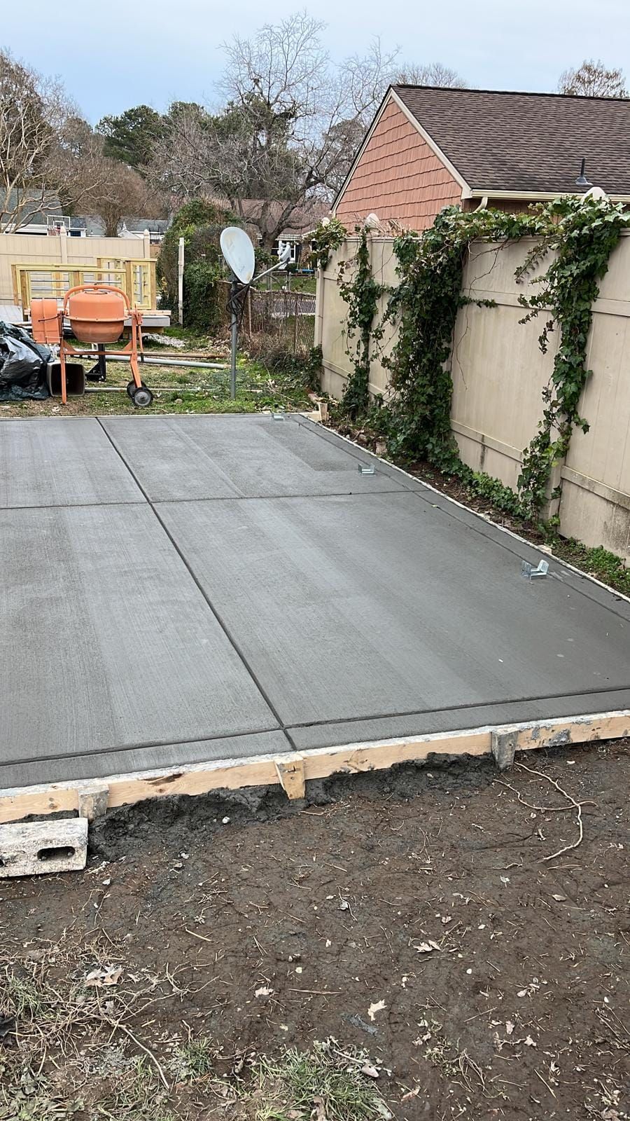 A concrete driveway is being built in front of a house.