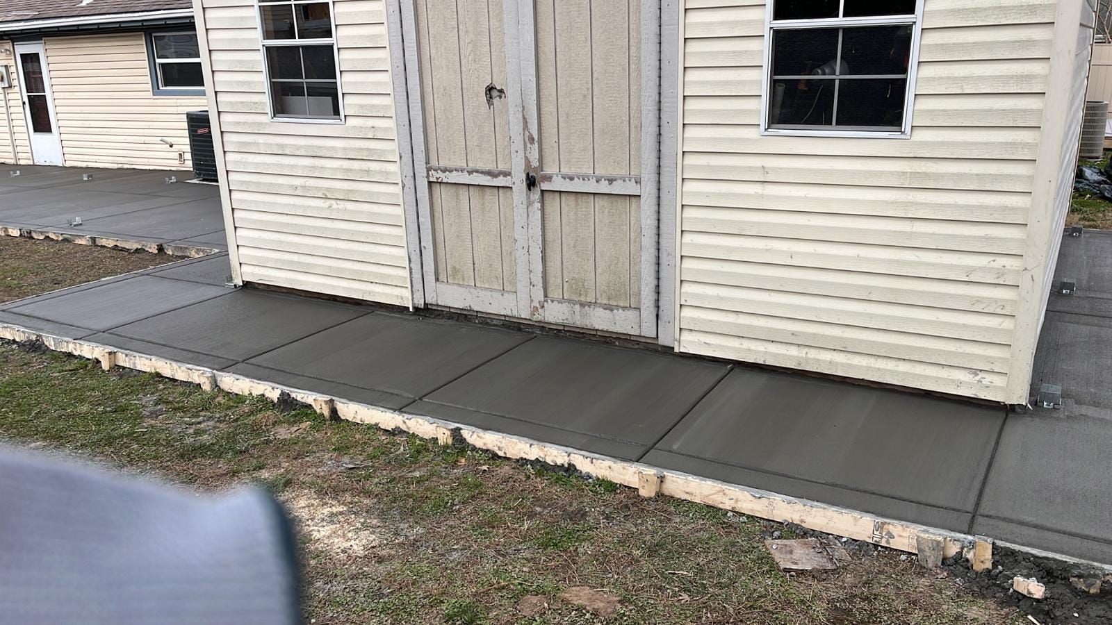 A concrete walkway is being built in front of a shed.