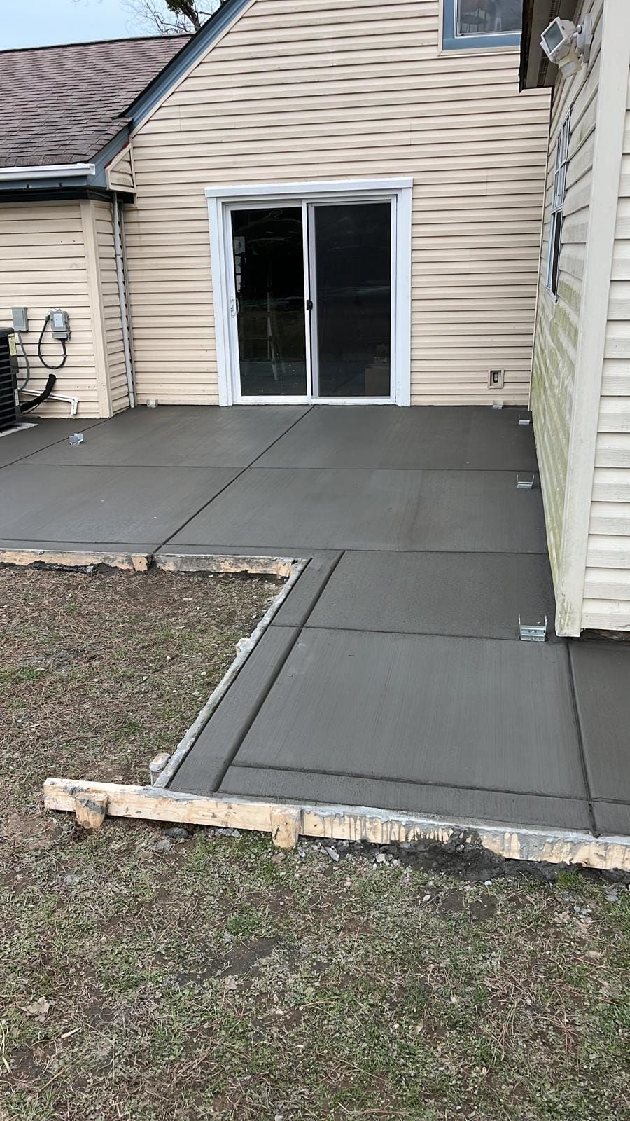 A concrete walkway is being built in front of a house.