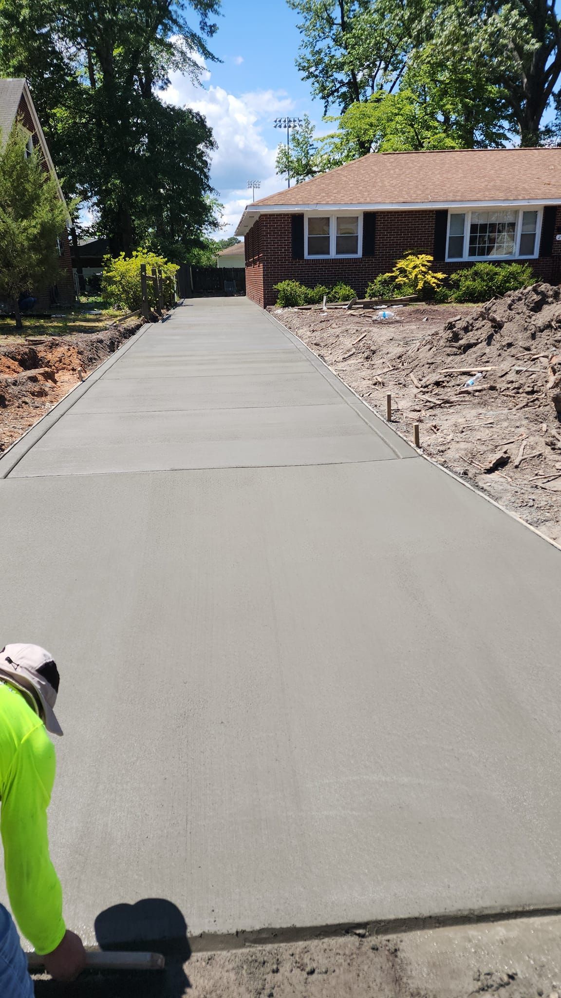 A man is working on a concrete driveway in front of a house.