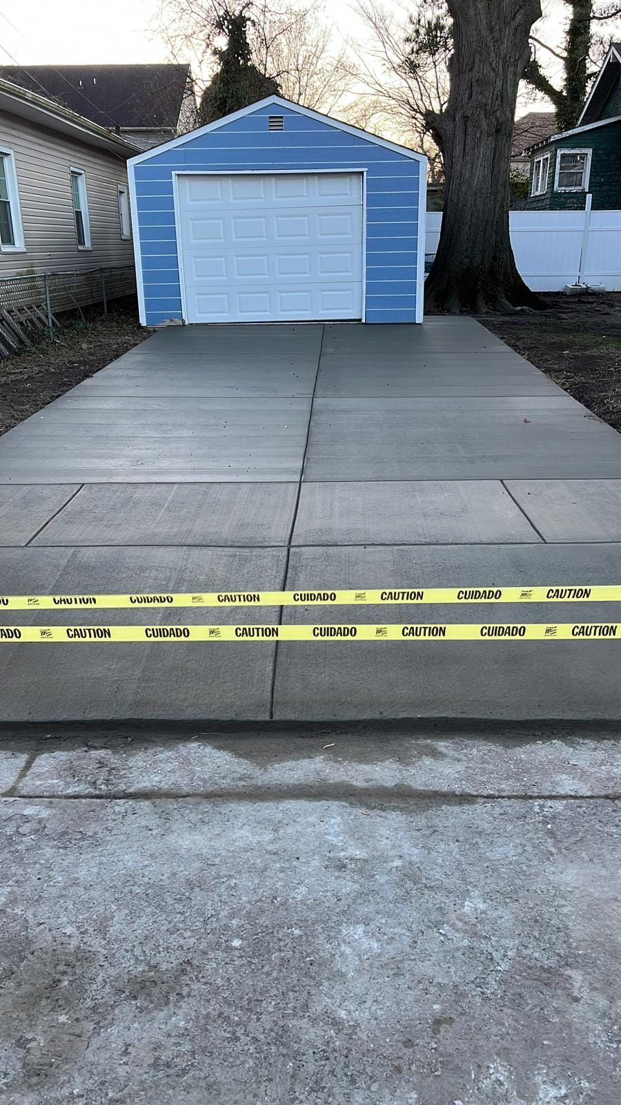 A concrete driveway with a blue garage in the background.