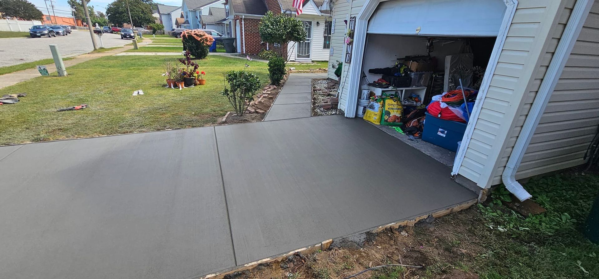A concrete driveway next to a house with a garage door open.