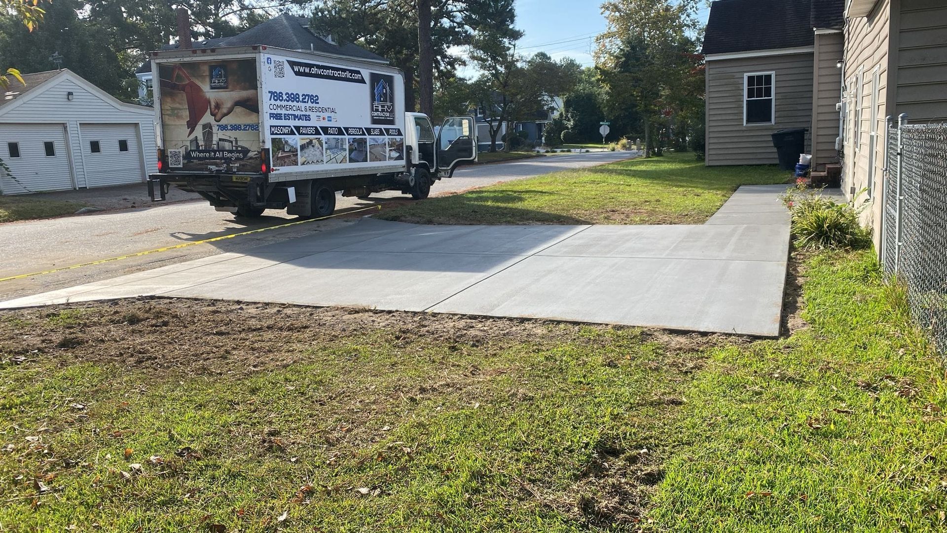 A white truck is parked in a driveway next to a house.