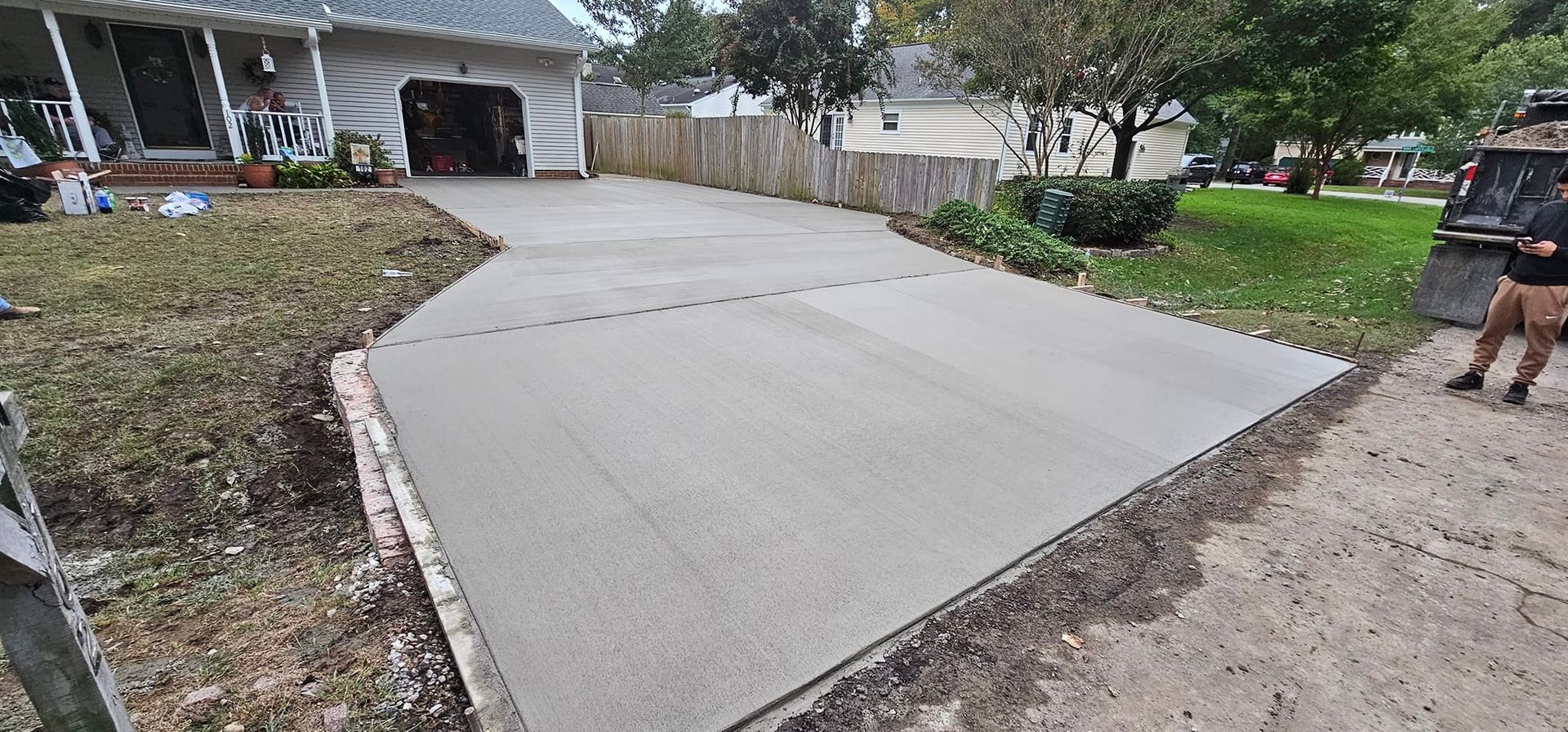 A concrete driveway is being built in front of a house.