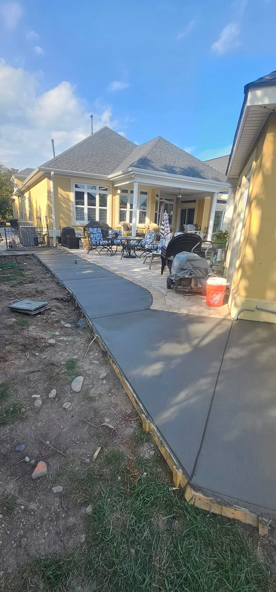 A yellow house with a concrete driveway in front of it.