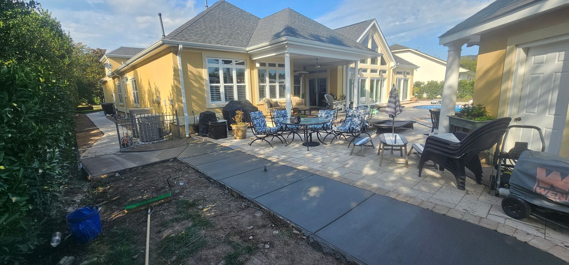 A large yellow house with a patio and chairs in front of it.