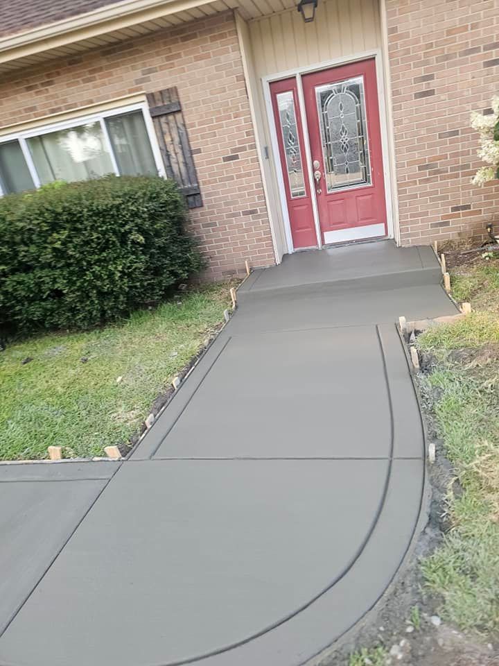 A concrete walkway is being built in front of a brick house.
