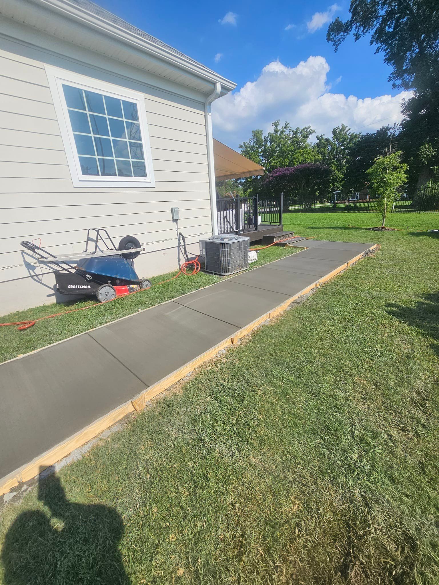 There is a concrete walkway leading to a house.