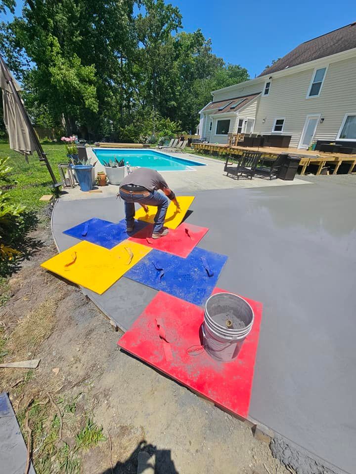 A man is painting a concrete patio in front of a pool.