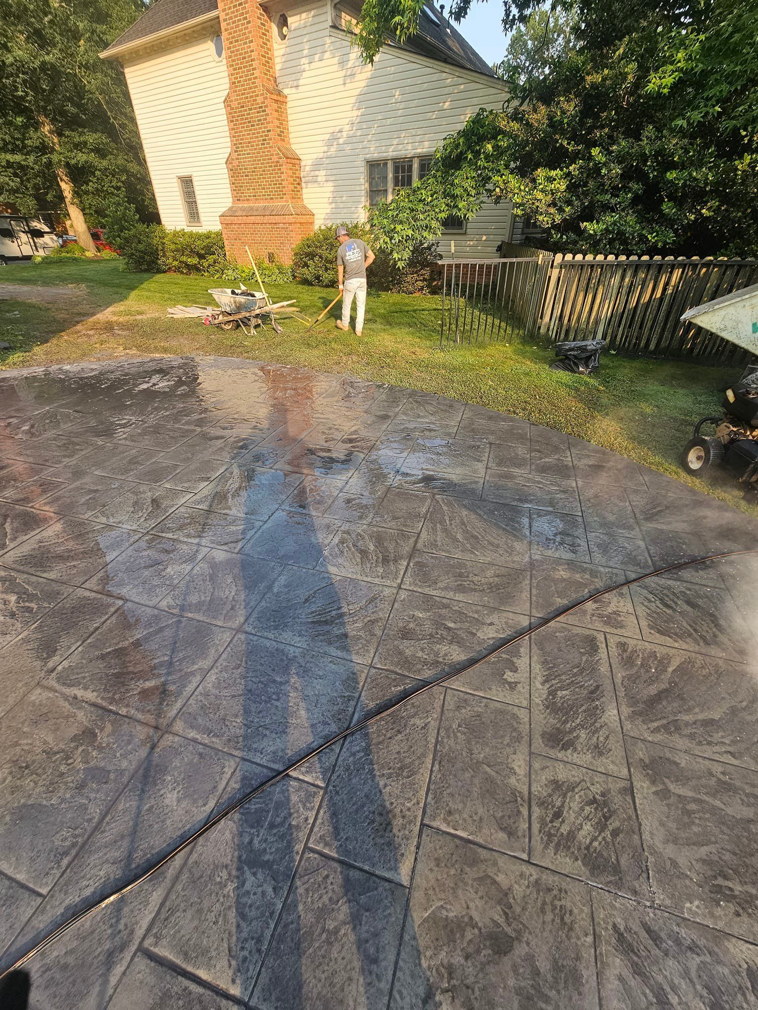 A man is using a pressure washer to clean a driveway in front of a house.