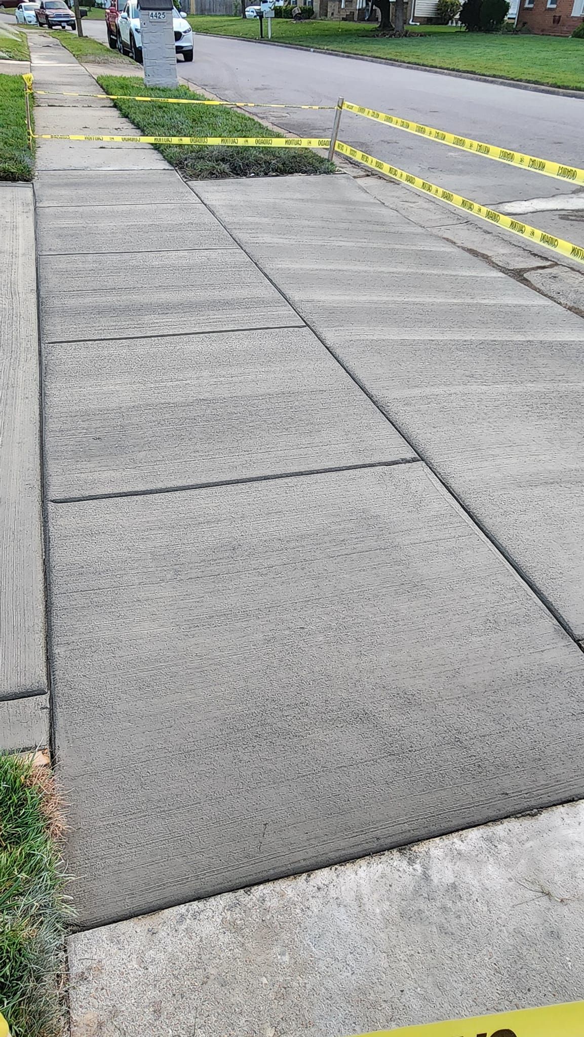 A sidewalk with a yellow caution tape along the side of it.