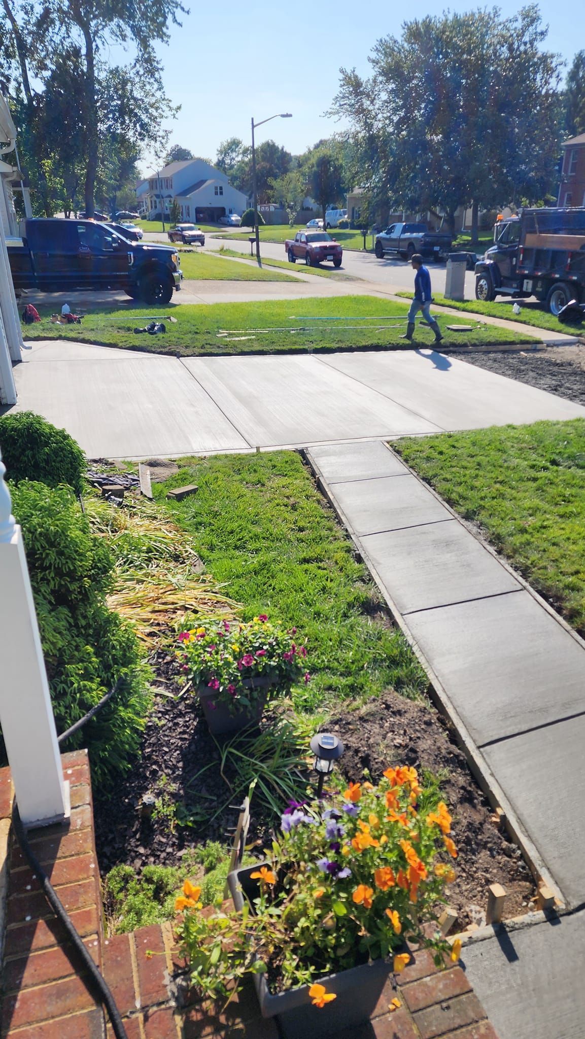 A person is walking down a sidewalk in front of a house.