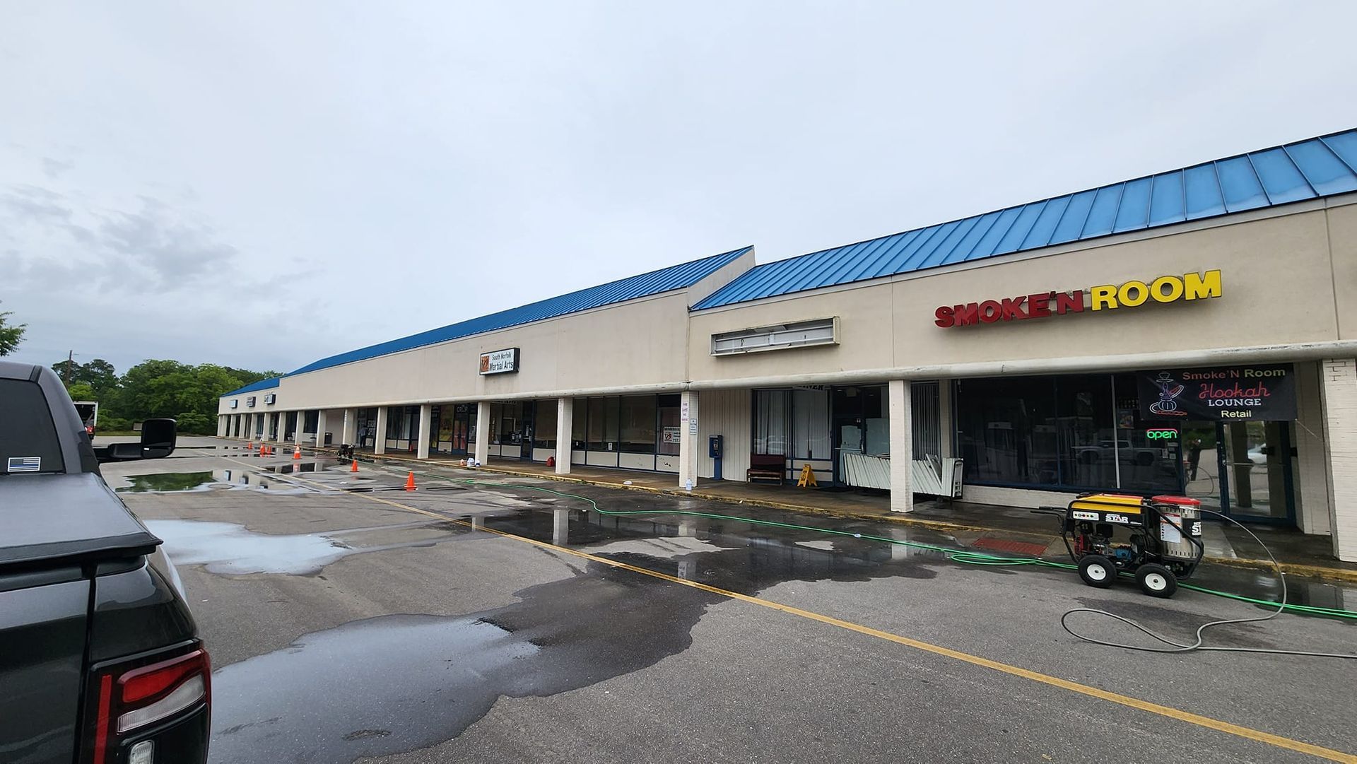 A car is parked in front of a building with a blue roof.