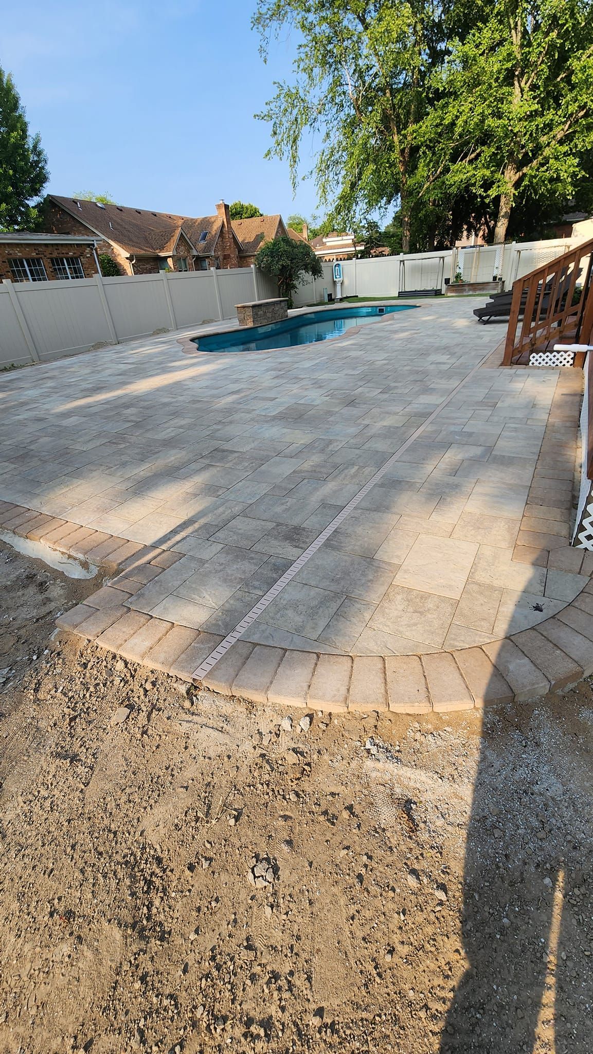 A large concrete patio with a swimming pool in the background.