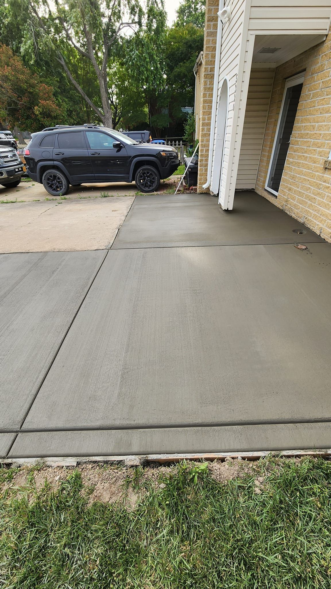 A black suv is parked in a driveway next to a brick building.