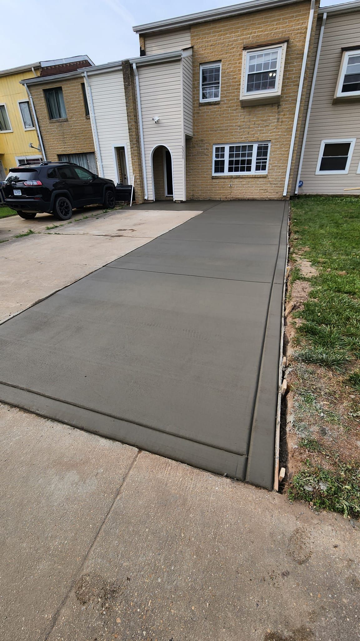 A concrete driveway is being built in front of a house.