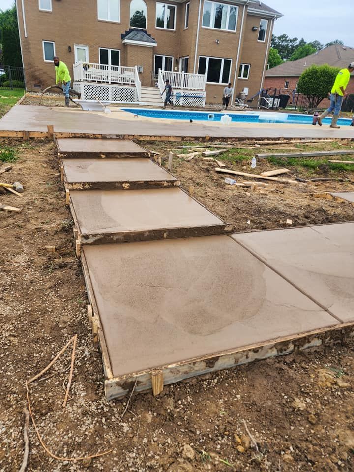 A concrete walkway is being built in front of a large house.