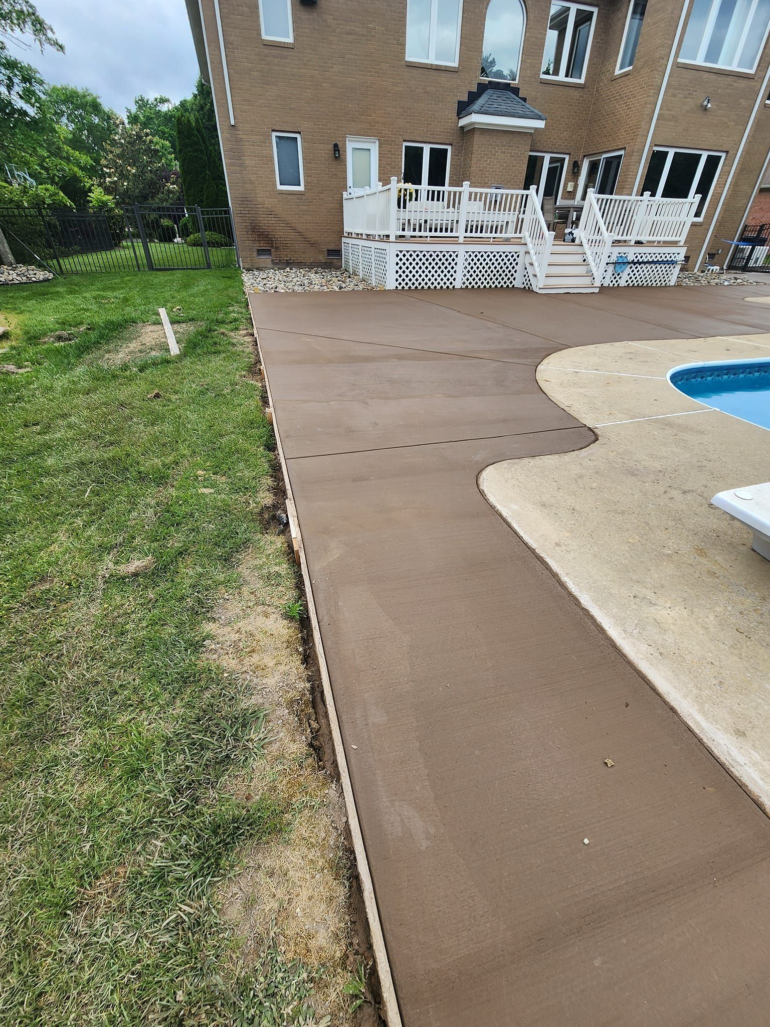 A concrete walkway leading to a swimming pool next to a house.