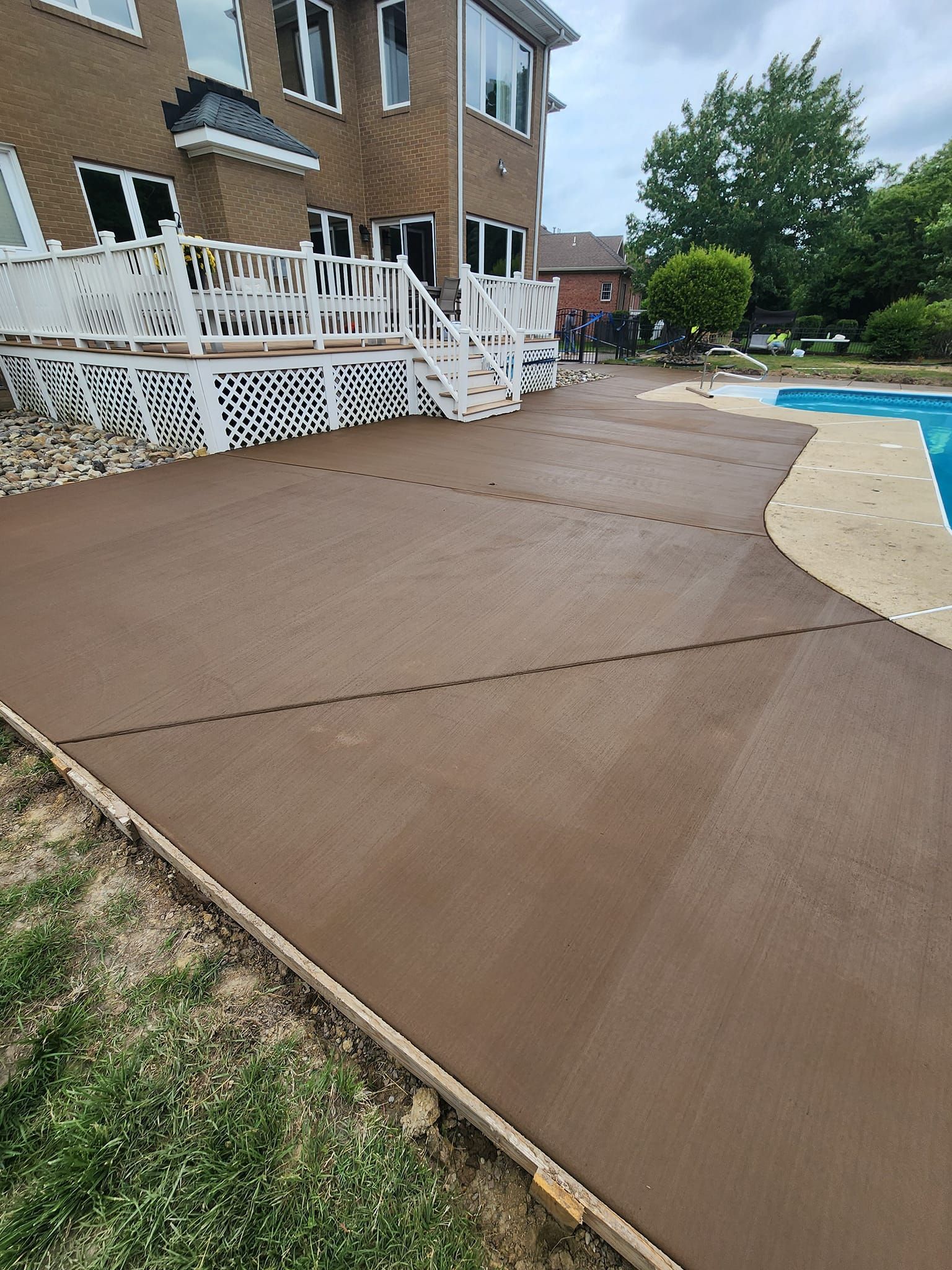 A patio with a deck and a pool in front of a house.