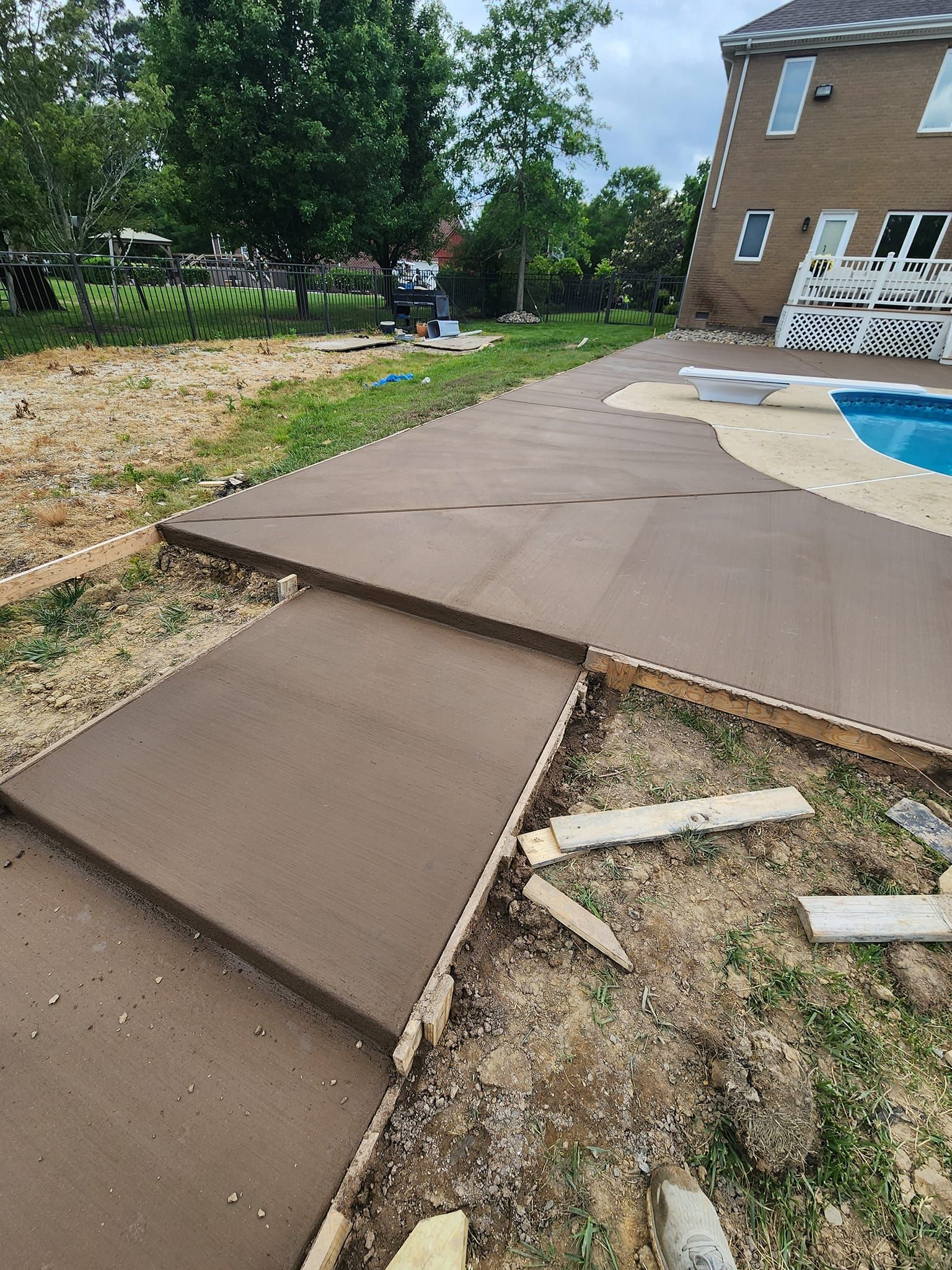 A concrete walkway is being built next to a swimming pool.