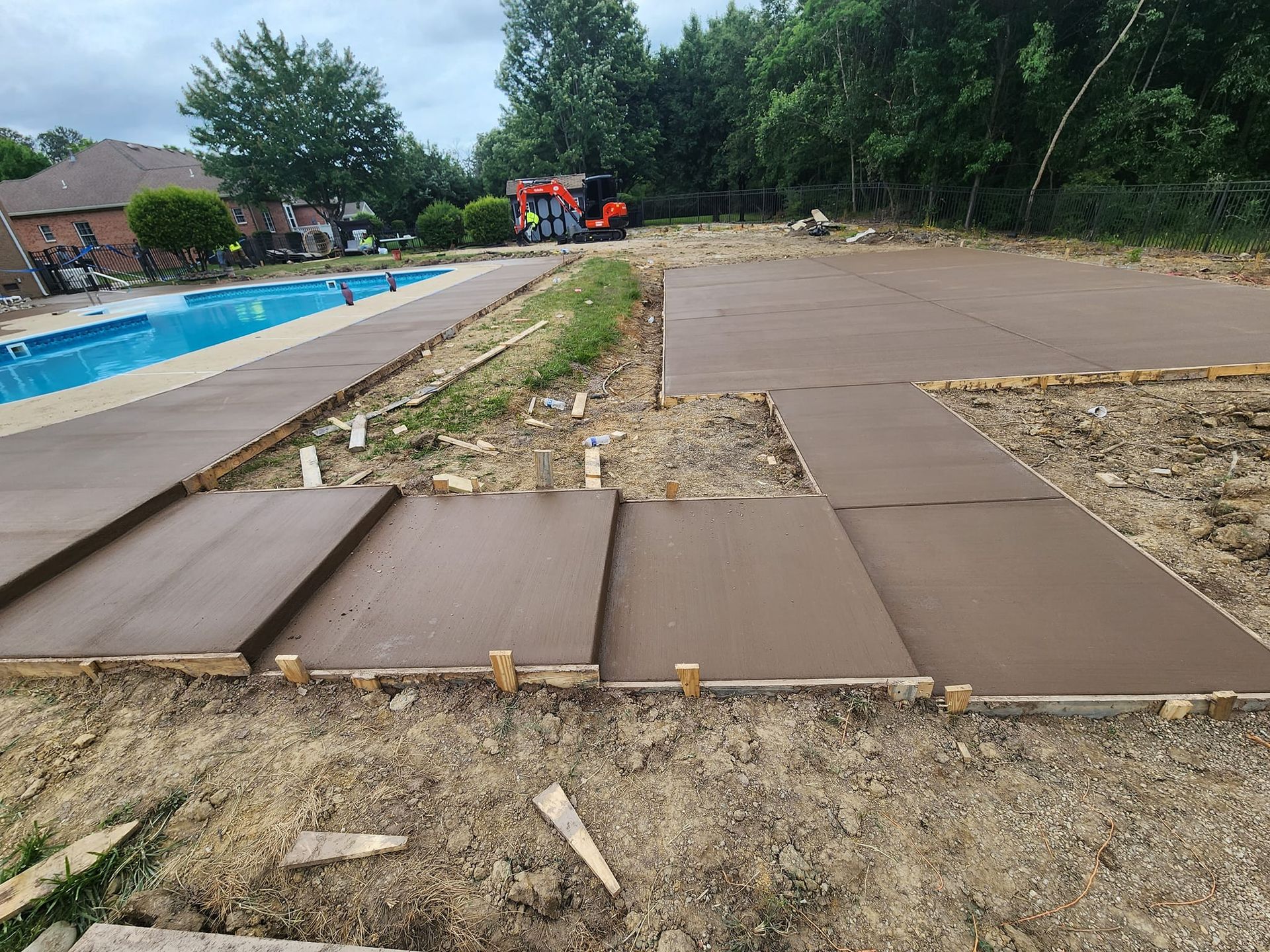 A concrete walkway is being built next to a swimming pool.