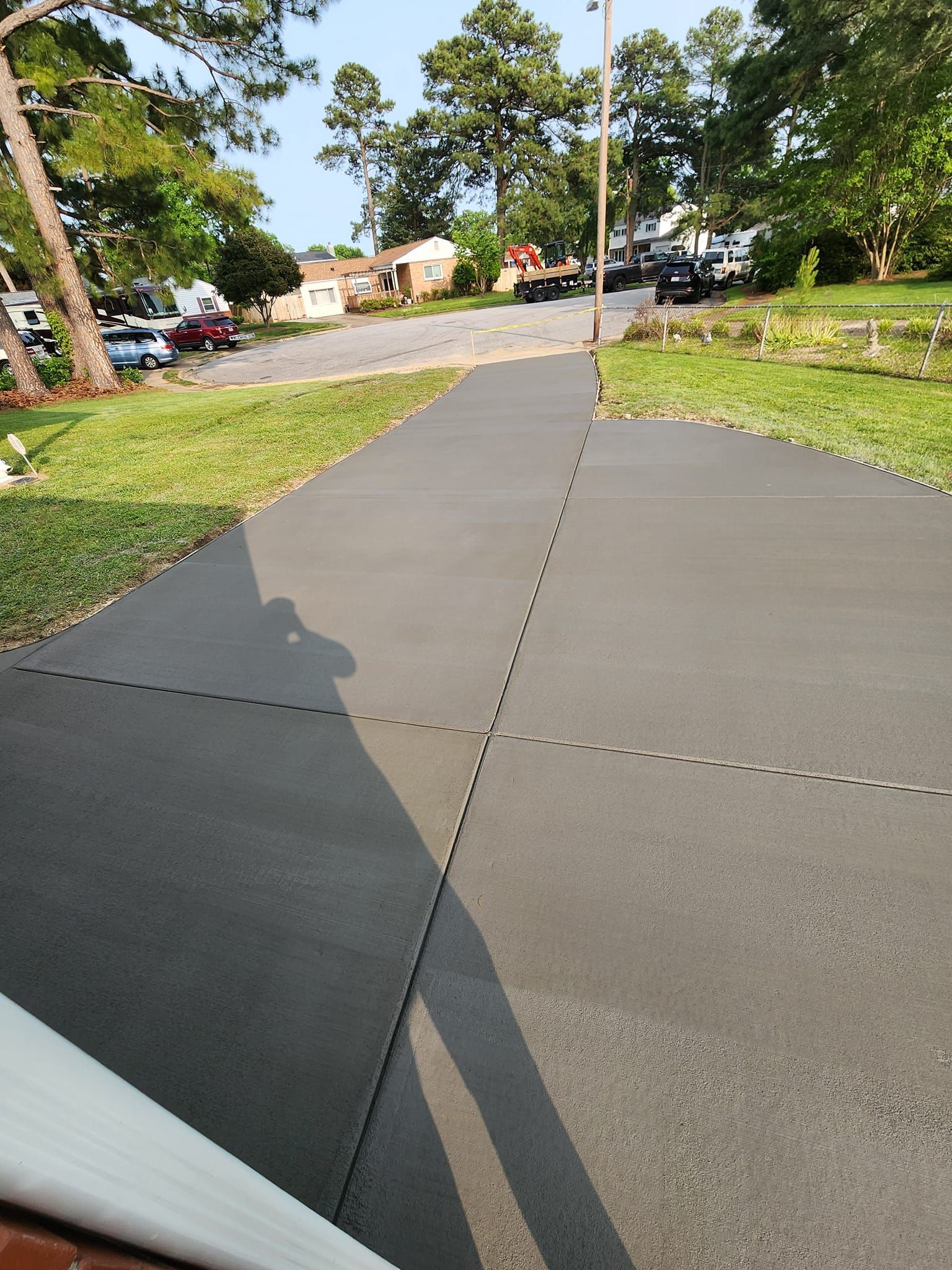 A shadow of a person is cast on a concrete sidewalk