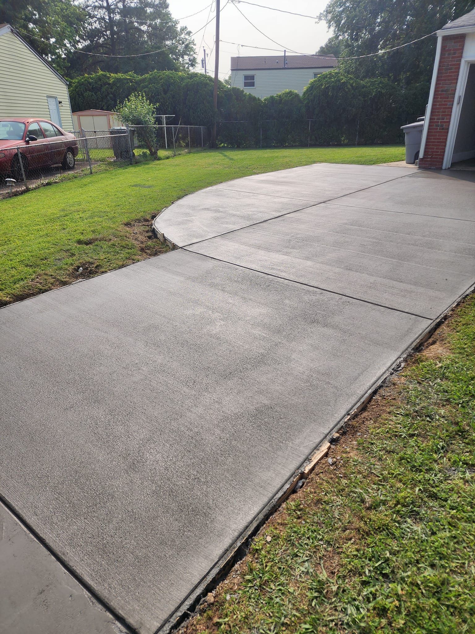 A concrete driveway is being built in the backyard of a house.