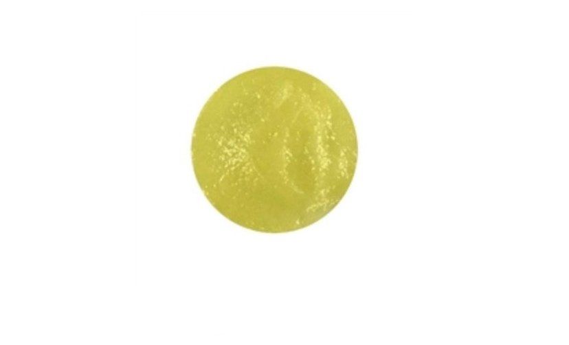 A yellow ball is sitting on a white surface.