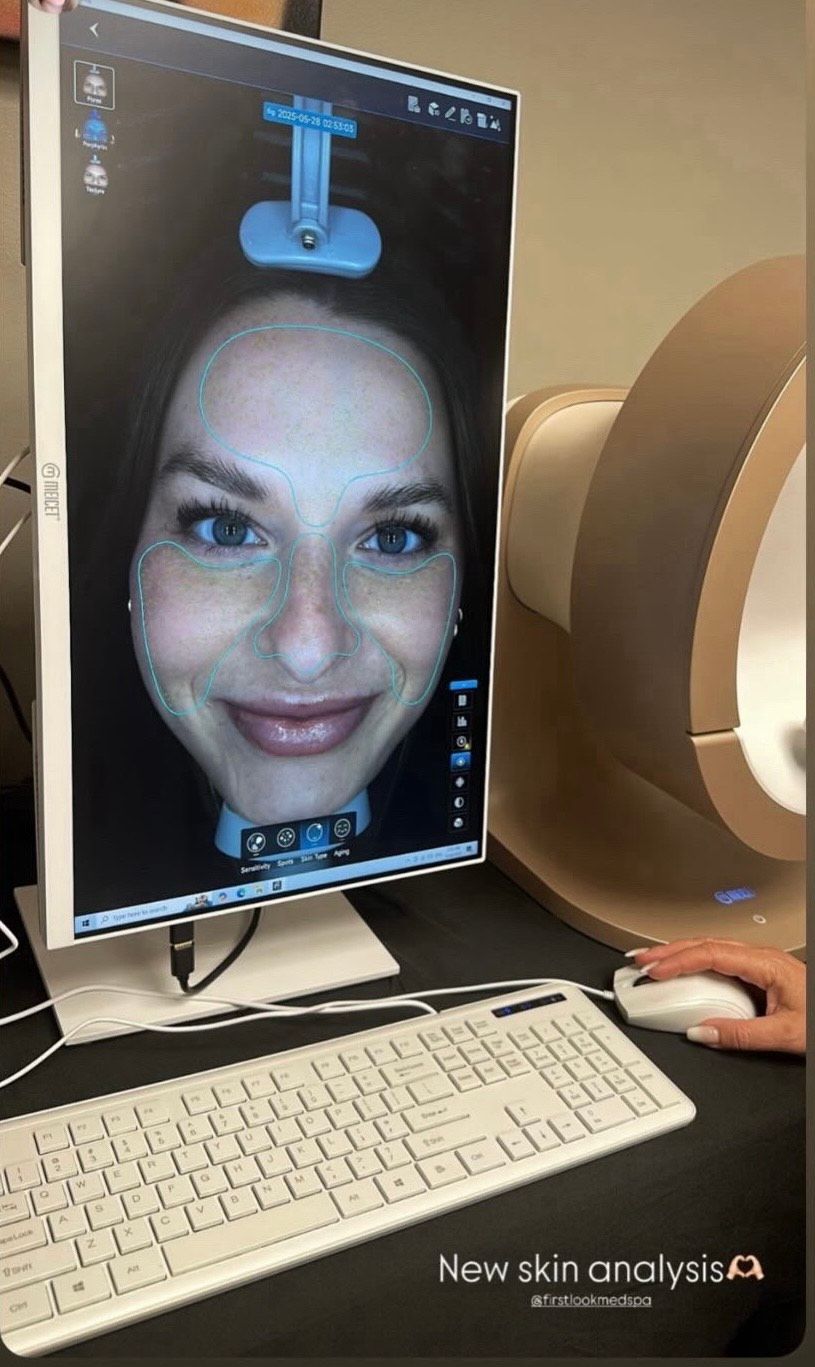 A woman is looking at her face on a computer screen.