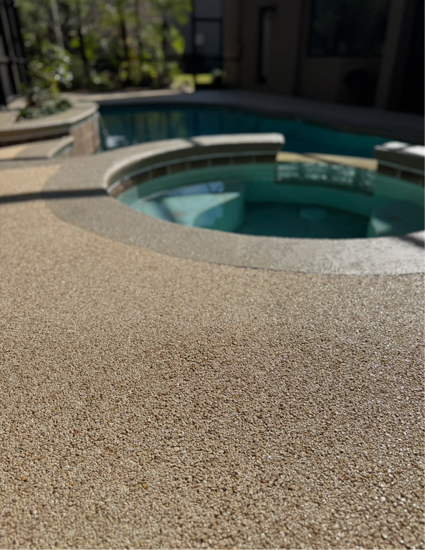 Textured patio beside a circular hot tub with teal water in a sunny backyard