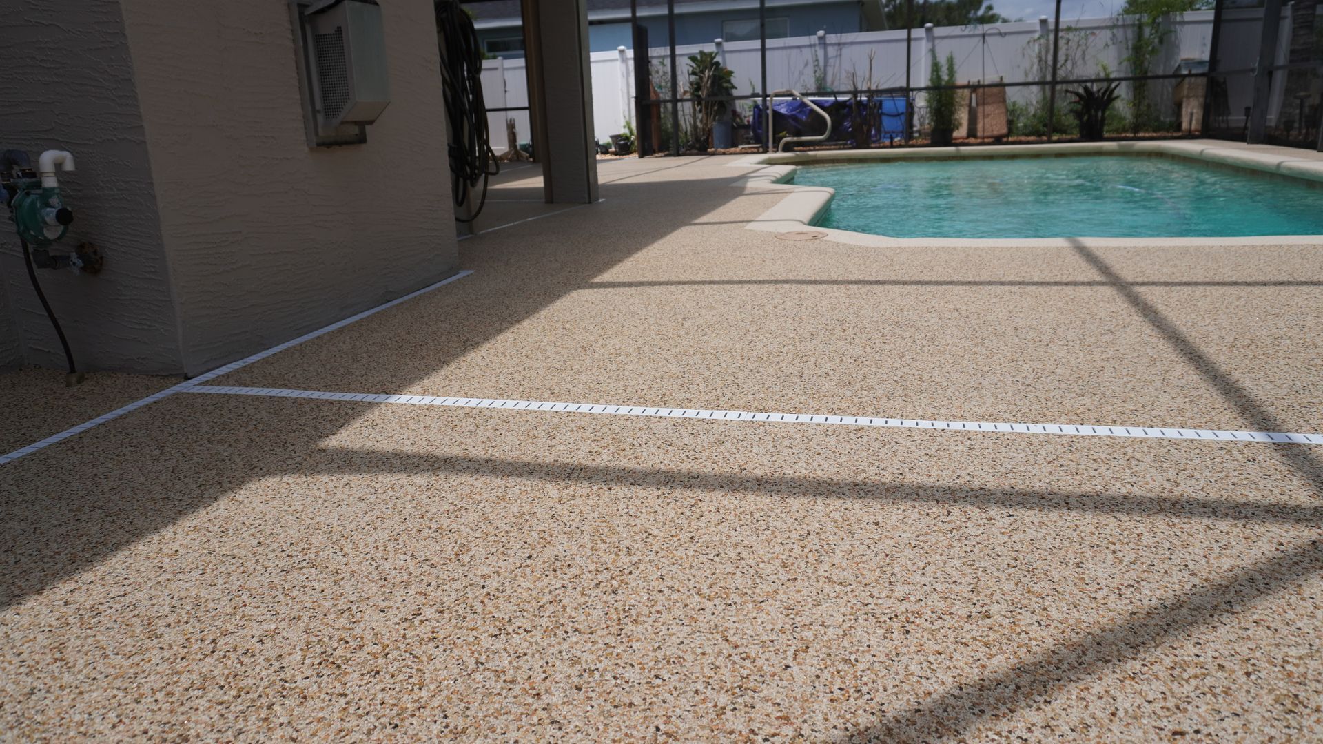 Poolside patio with speckled concrete, white lane lines, and a swimming pool in the background