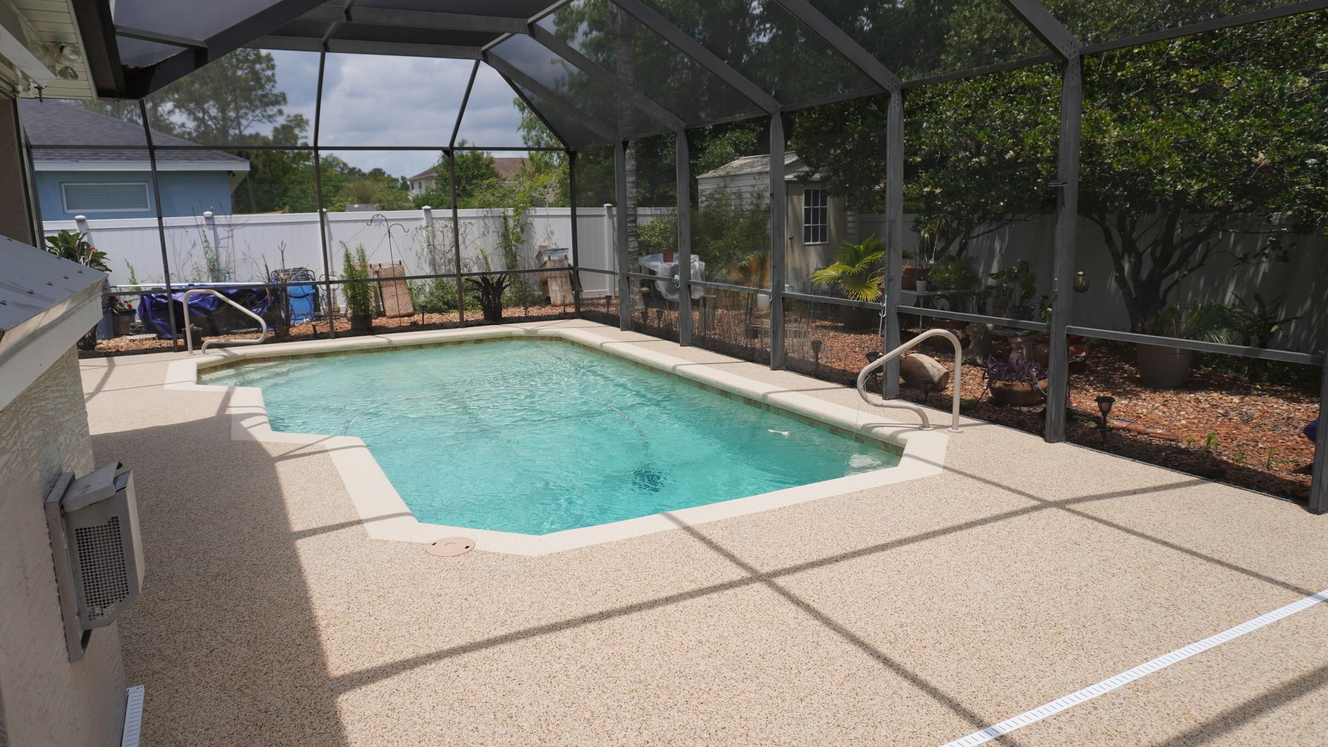 Backyard pool with turquoise water under a screened enclosure and surrounding patio.