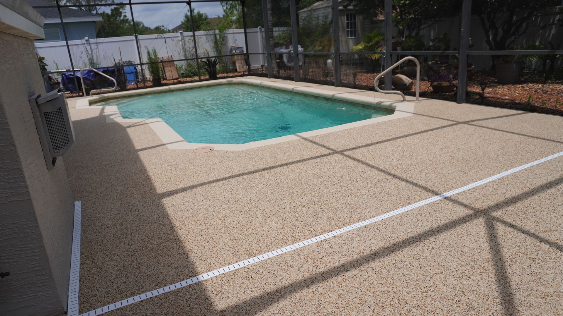 Backyard swimming pool with tan patio, fence, and covered swim lane markings