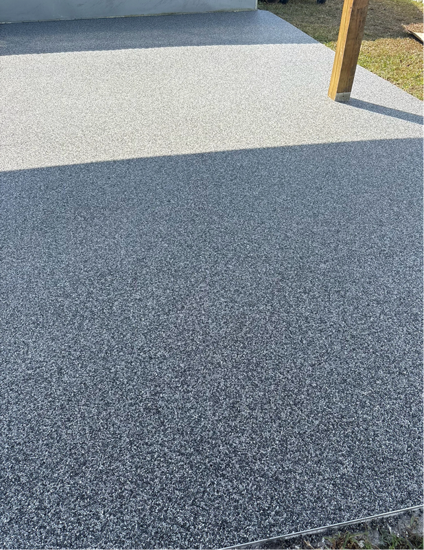 Freshly coated gray textured porch or patio surface with a wooden post and bright sunlight shadows