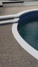 Curved swimming pool edge with blue tiled wall and textured deck flooring