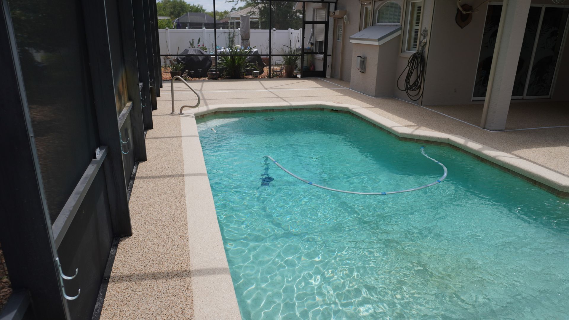 Outdoor apartment pool with clear blue water and beige pool deck, viewed from the side