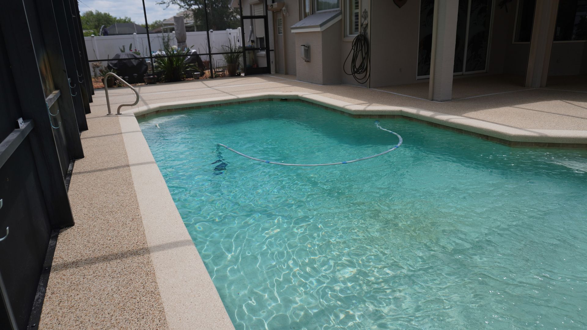 Outdoor swimming pool with clear turquoise water beside a patio and apartment buildings.