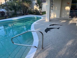 Swimming pool with metal handrail and black fish-shaped deck decorations near the water