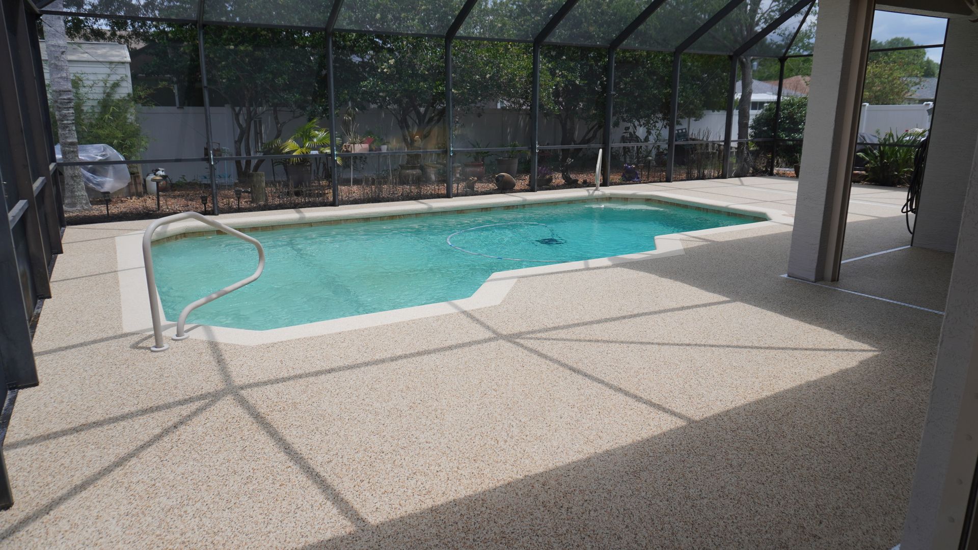 Covered outdoor swimming pool with turquoise water and a screened patio area