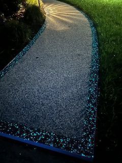 Curved gravel path bordered with glowing blue lights at dusk
