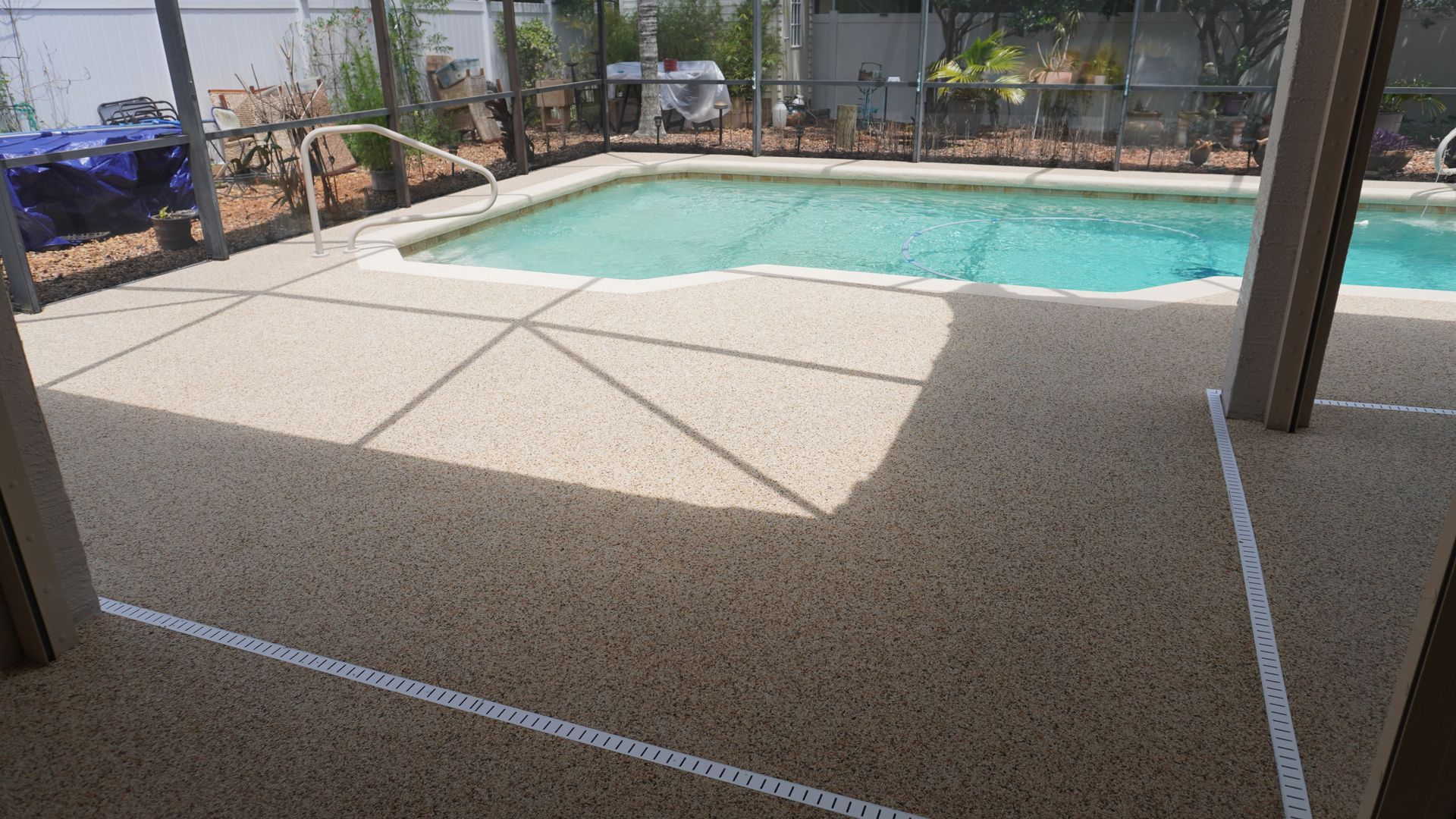 Covered patio overlooking a turquoise backyard pool and fence-lined yard
