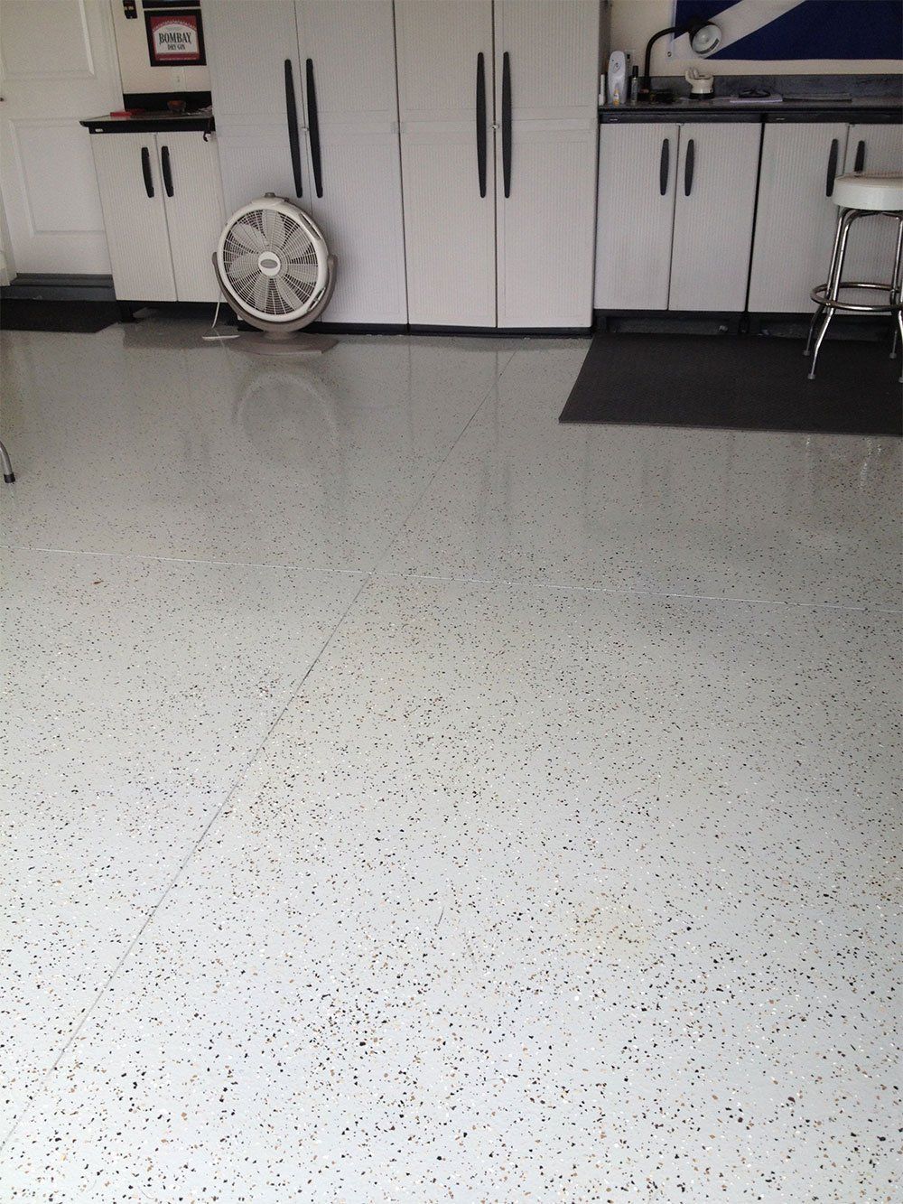 Spacious garage with white cabinets, a wall fan, and a polished speckled floor