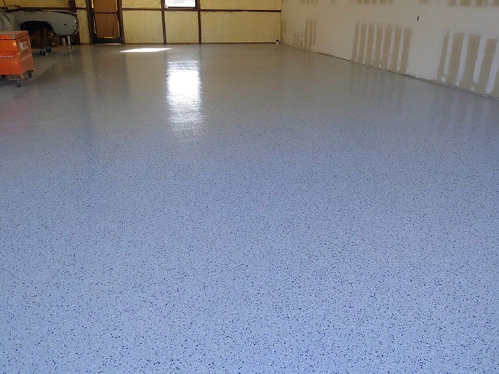 Empty speckled epoxy garage floor with closed doors in the background