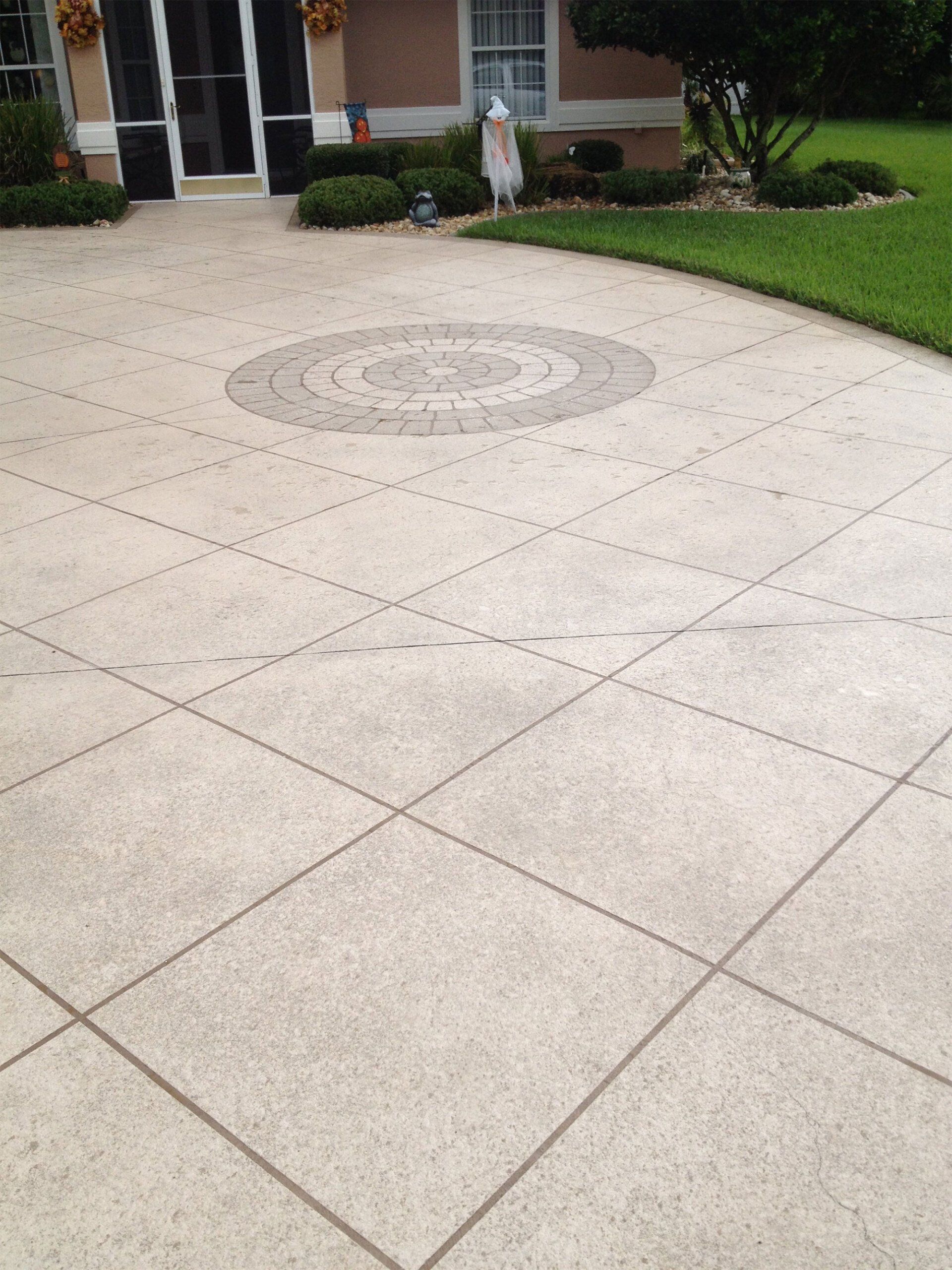 Front walkway of a house with a decorative circular tile design and green lawn nearby
