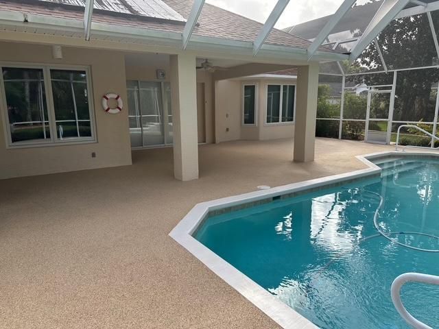 Covered patio beside a turquoise swimming pool, with sliding glass doors and beige columns.
