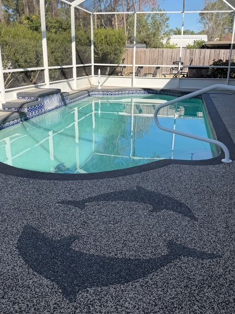 Backyard swimming pool with blue water, white handrails, and a dark wet patio in the foreground