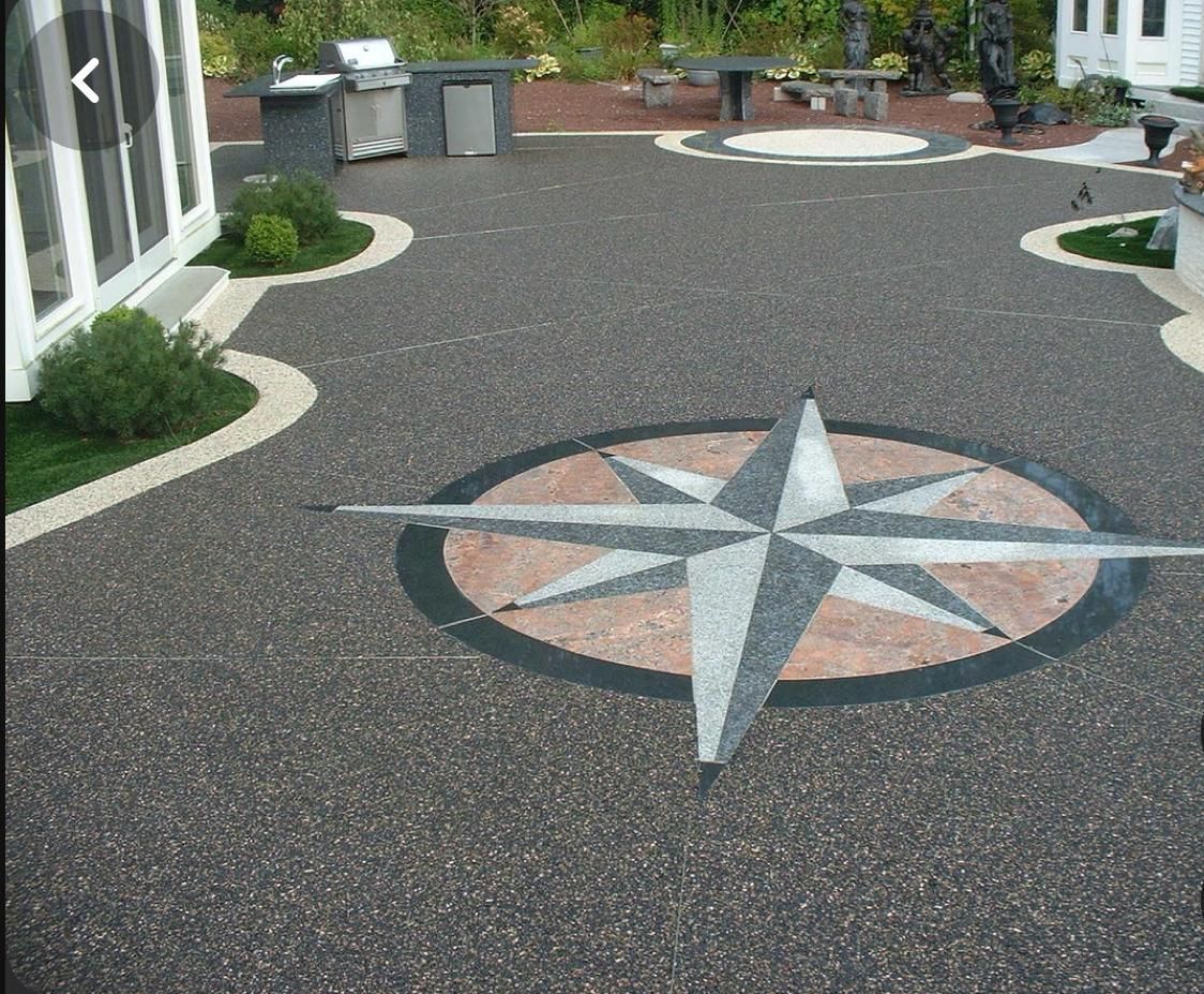Decorative compass rose in a paved courtyard with patio seating and planters