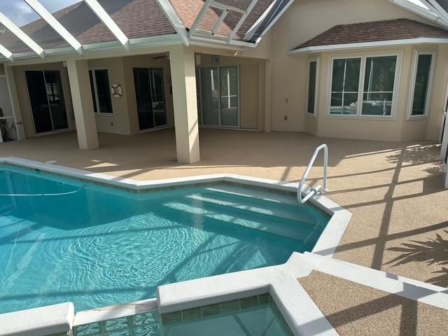 Backyard swimming pool beside a covered patio and beige house exterior