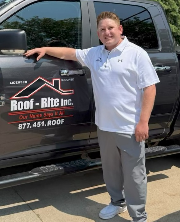 Man in white shirt stands next to a truck with 